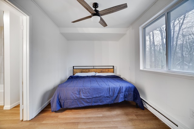 bedroom with light wood-style flooring, a ceiling fan, baseboards, and baseboard heating