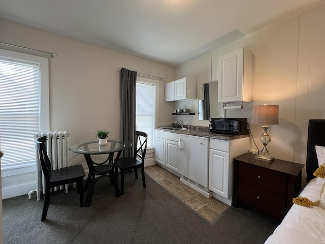 kitchen featuring a sink, black microwave, dishwashing machine, and white cabinets