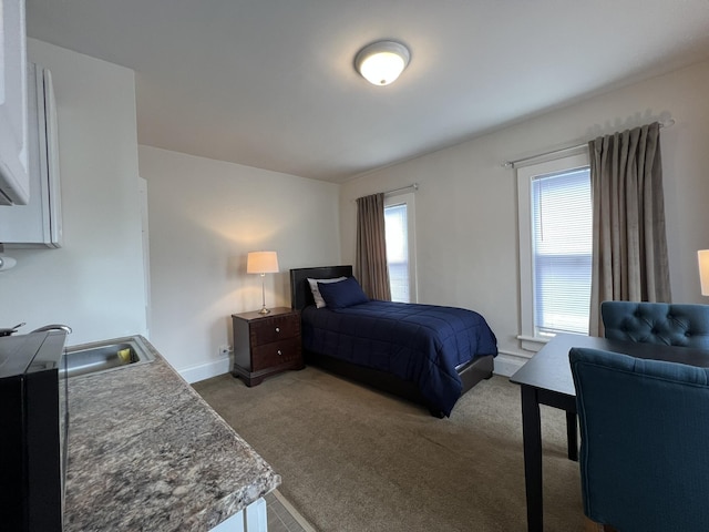 carpeted bedroom with baseboards and a sink