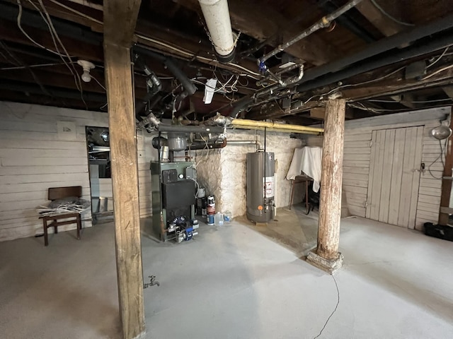 unfinished below grade area featuring wooden walls, heating unit, and water heater