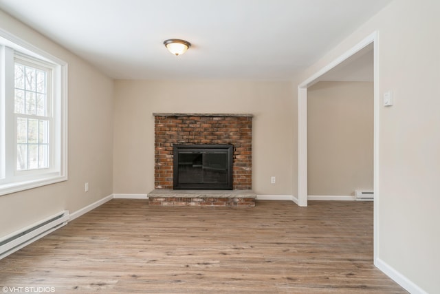 unfurnished living room with a baseboard heating unit, wood finished floors, a fireplace, baseboards, and baseboard heating