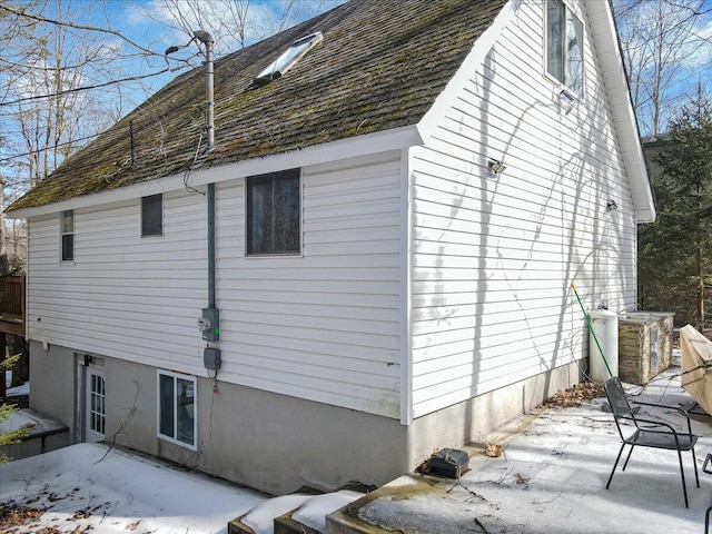 view of home's exterior with a patio and a shingled roof