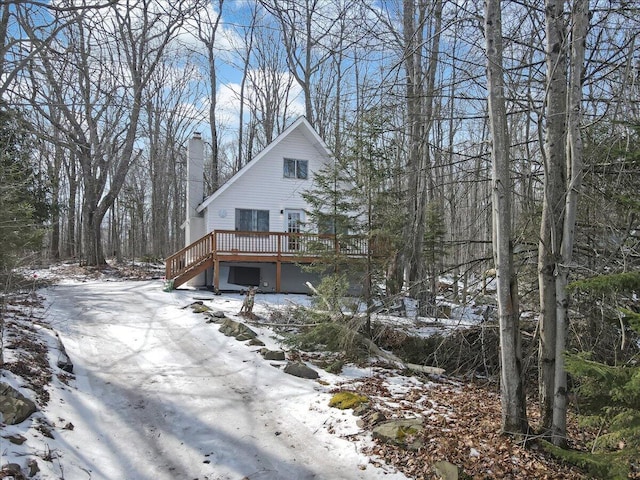 view of snowy exterior with a deck and a chimney