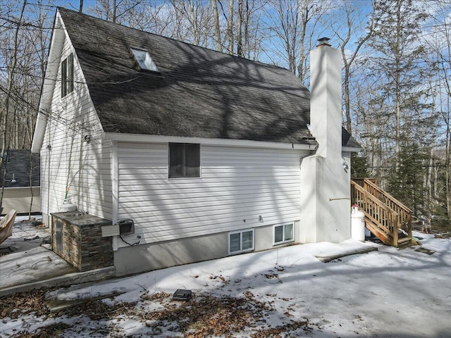 snow covered property featuring roof with shingles and a chimney