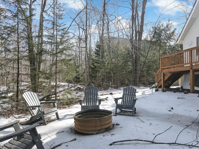 snow covered patio with a fire pit, stairs, and a deck