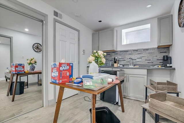 kitchen with a sink, visible vents, tasteful backsplash, and gray cabinets