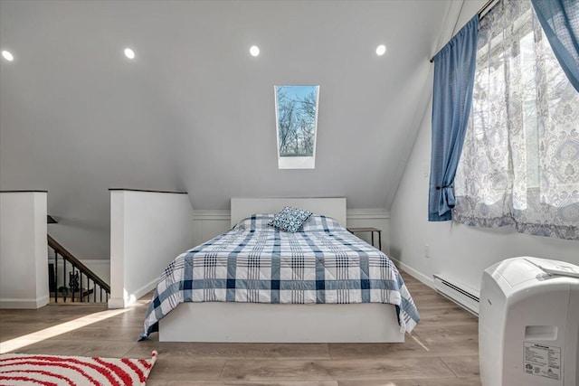 bedroom with baseboards, baseboard heating, wood finished floors, and vaulted ceiling