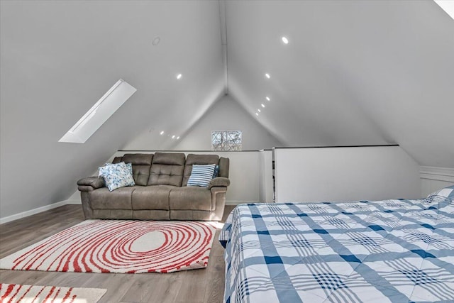 bedroom with vaulted ceiling with skylight, wood finished floors, and baseboards