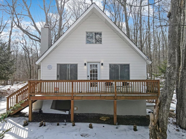 snow covered property with a deck and a chimney