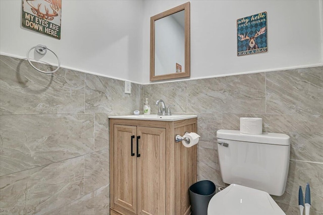 half bath featuring vanity, tile walls, and toilet