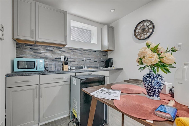 kitchen featuring a sink, gray cabinetry, fridge, tasteful backsplash, and light wood-type flooring