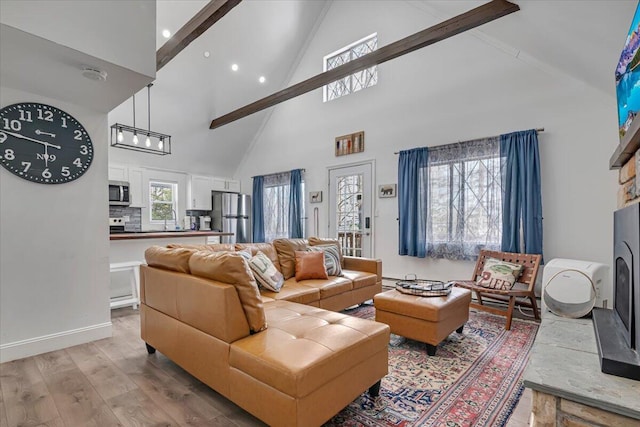 living area with baseboards, lofted ceiling, a fireplace with raised hearth, and light wood finished floors