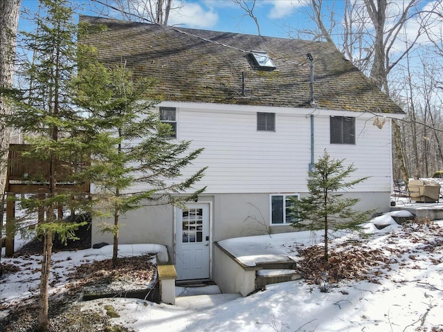 view of snow covered exterior featuring roof with shingles