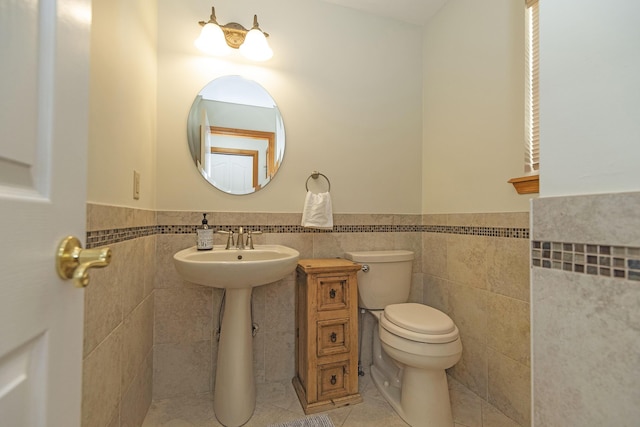 half bathroom with toilet, wainscoting, and tile walls
