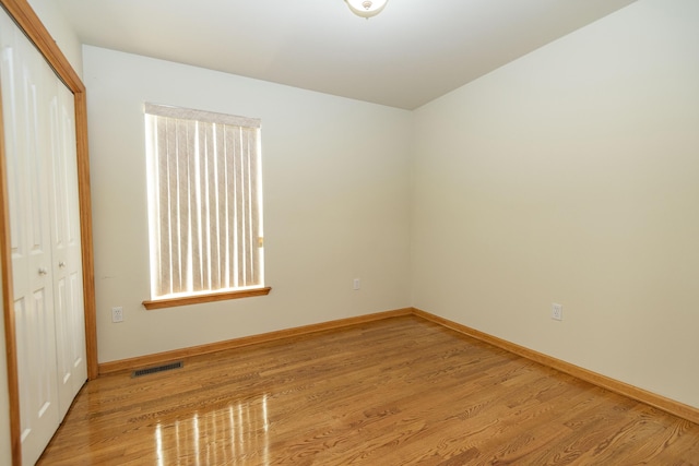 unfurnished bedroom featuring baseboards, light wood-style flooring, and a closet