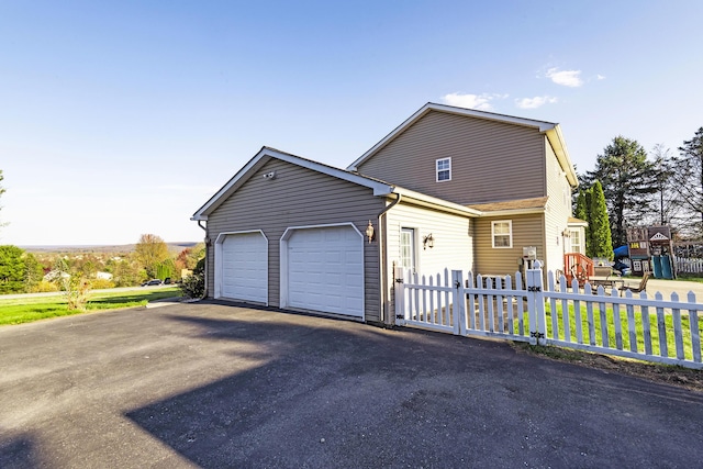 view of front of house featuring driveway, an attached garage, and fence