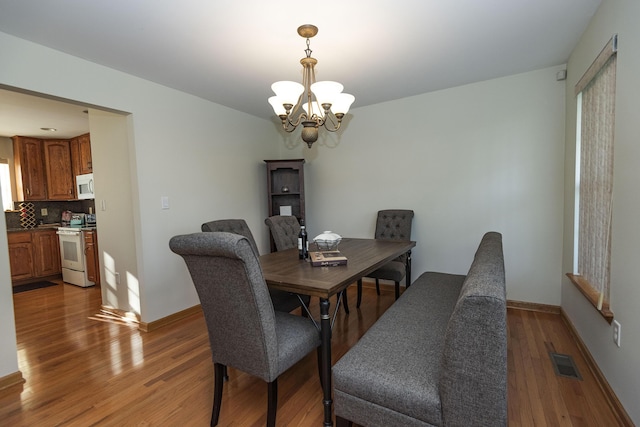 dining space with a notable chandelier, visible vents, baseboards, and light wood-type flooring