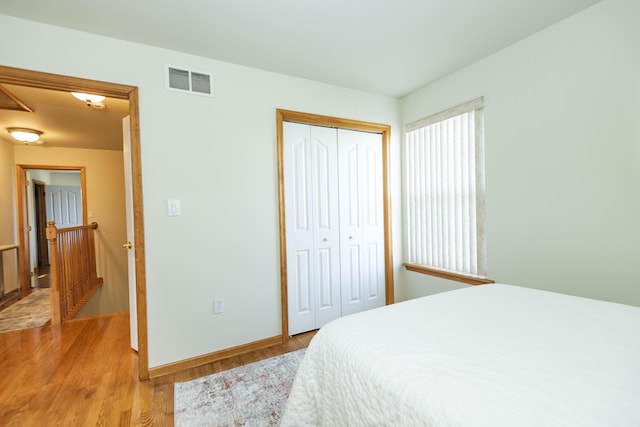 bedroom featuring a closet, visible vents, baseboards, and light wood-style floors