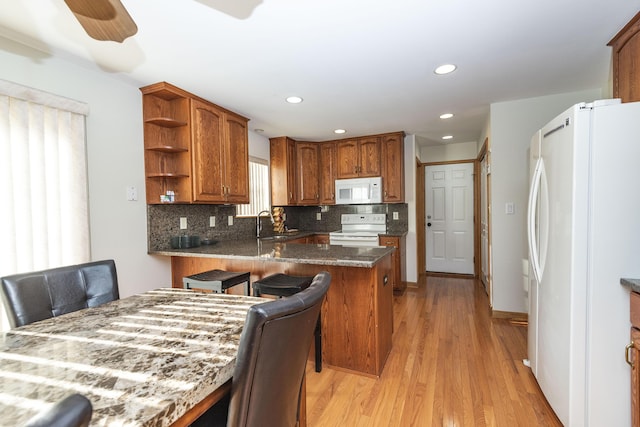 kitchen featuring white appliances, decorative backsplash, open shelves, light wood-style floors, and brown cabinets