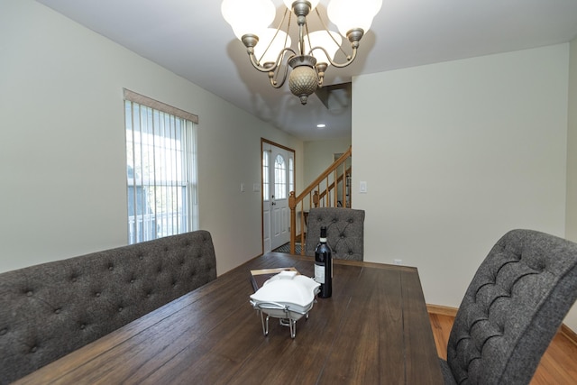 dining area with an inviting chandelier, stairway, and wood finished floors