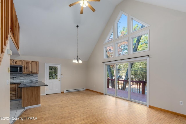 interior space with a baseboard heating unit, high vaulted ceiling, light wood-style flooring, and baseboards