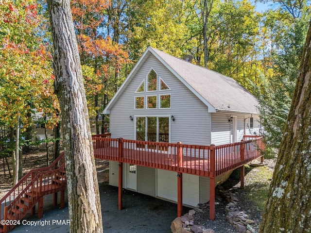 back of property with a shingled roof and a wooden deck