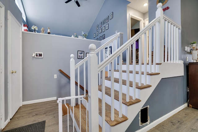 staircase with lofted ceiling, baseboards, and wood finished floors