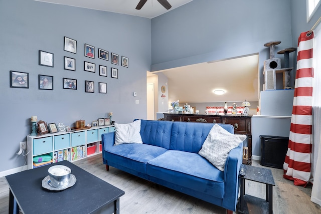 living area featuring high vaulted ceiling, baseboards, a ceiling fan, and wood finished floors