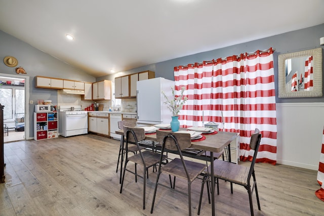 dining room with vaulted ceiling and light wood finished floors