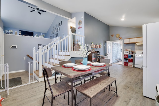 dining space with vaulted ceiling with beams, ceiling fan, baseboards, stairway, and light wood-type flooring