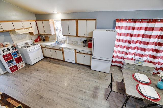 kitchen featuring white appliances, light wood-style flooring, light countertops, under cabinet range hood, and a sink