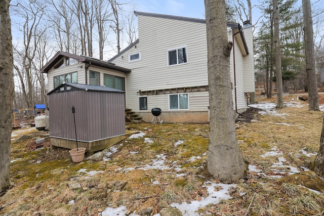 rear view of property with an outdoor structure, a chimney, and a shed