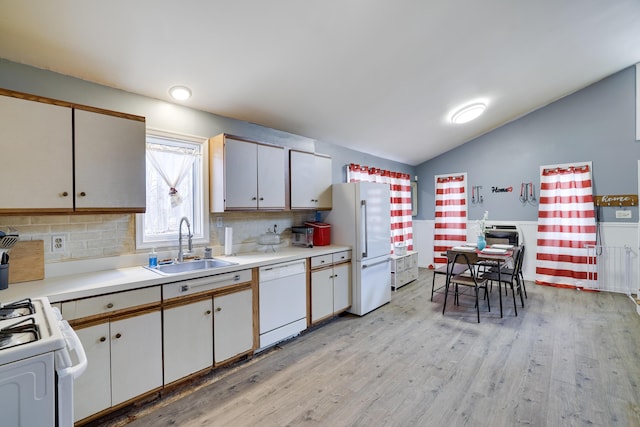 kitchen with white appliances, light countertops, a sink, and light wood finished floors