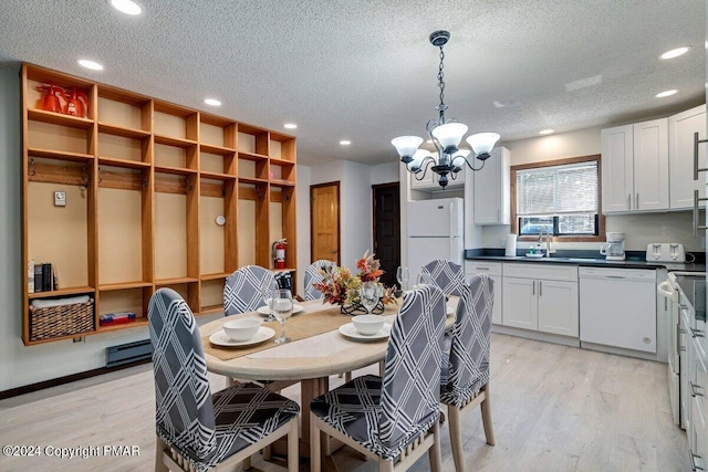 dining area with light wood-style floors, a chandelier, a textured ceiling, and a baseboard heating unit