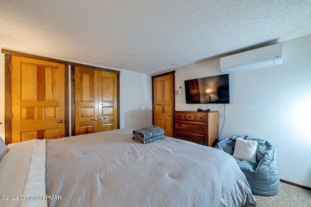 bedroom with carpet, a wall unit AC, a textured ceiling, and baseboards