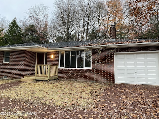 view of front of home with a garage, a chimney, and brick siding