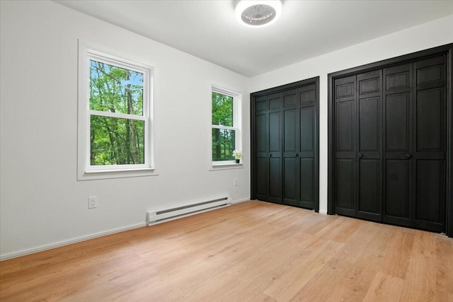 754 Clubhouse Dr, East Stroudsburg, PA 18302 - unfurnished bedroom with baseboard heating, multiple closets, and light wood finished floors