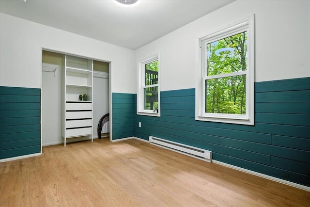 754 Clubhouse Dr, East Stroudsburg, PA 18302 - unfurnished bedroom with a baseboard radiator, light wood finished floors, a wainscoted wall, wood walls, and a closet