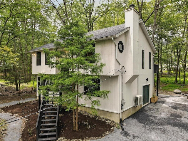 754 Clubhouse Dr, East Stroudsburg, PA 18302 - view of front facade featuring a chimney, stairway, roof with shingles, and view of scattered trees