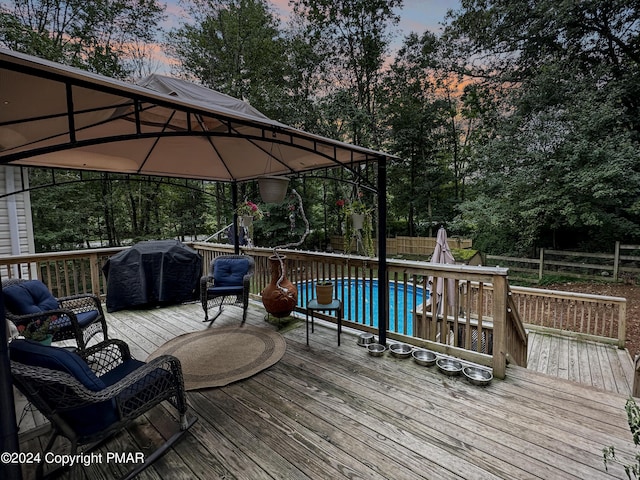 228 Wilbur Bloom Blvd, East Stroudsburg, PA 18302 - deck at dusk featuring grilling area, an outdoor pool, a gazebo, and fence