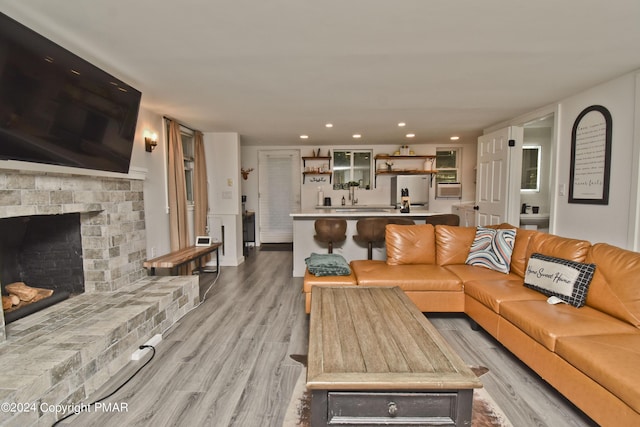 living room with a fireplace, light wood-style flooring, and recessed lighting