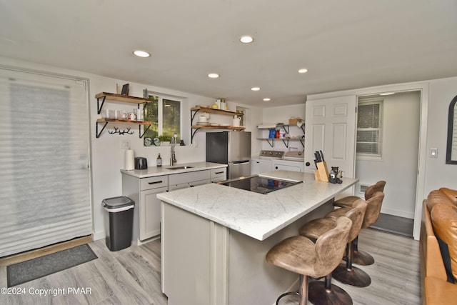 kitchen featuring open shelves, freestanding refrigerator, a sink, independent washer and dryer, and black electric cooktop