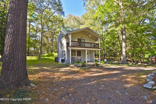 view of front of home with a chimney and a balcony