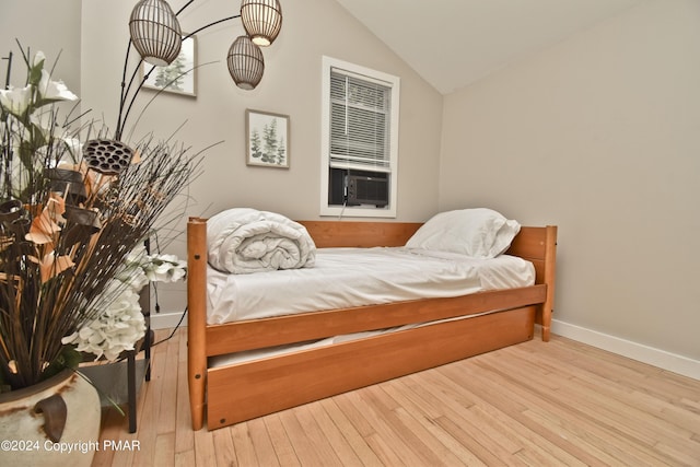 bedroom with lofted ceiling, hardwood / wood-style floors, cooling unit, and baseboards