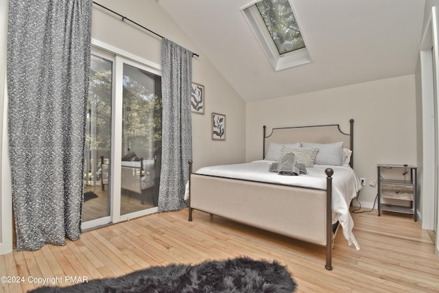 bedroom featuring lofted ceiling with skylight, multiple windows, access to exterior, and wood finished floors