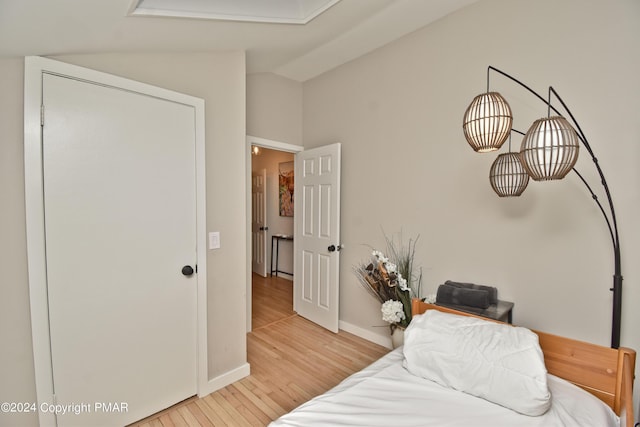 bedroom featuring lofted ceiling, light wood-style flooring, and baseboards