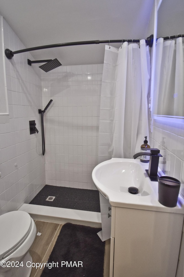 full bathroom featuring tile walls, a tile shower, and vanity