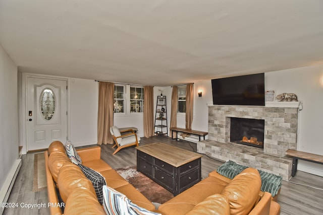 living room with a fireplace with raised hearth, baseboard heating, and wood finished floors