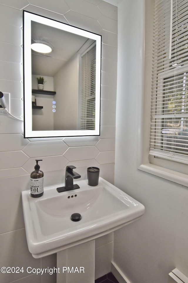 bathroom with tasteful backsplash, a sink, and tile walls