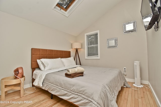 bedroom with lofted ceiling with skylight, baseboards, and hardwood / wood-style flooring